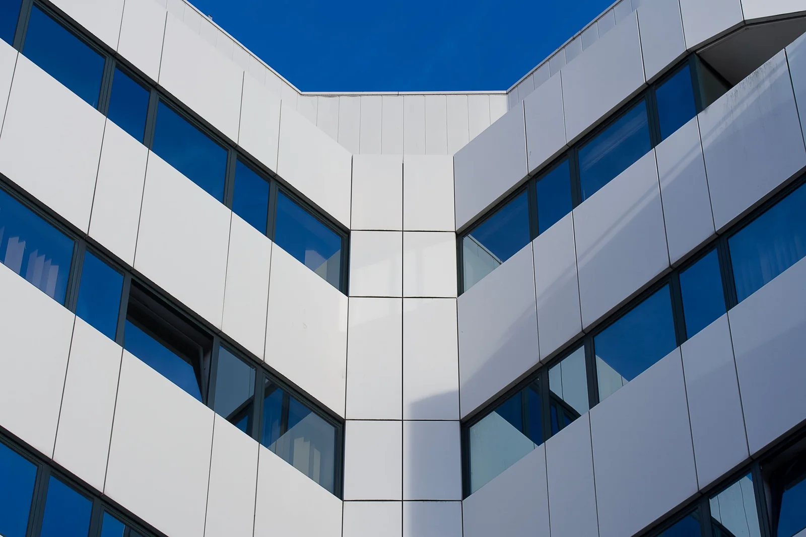 Low angle view of modern office building facade in Rijswijk, striking blue sky.